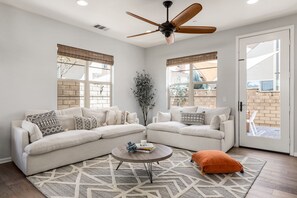 A modern living room with two white sofas, a coffee table, and a ceiling fan.