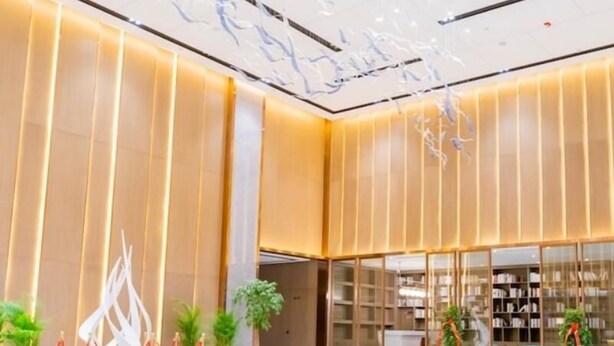 Um hall espaçoso com design moderno, apresentando um balcão de recepção, portas de vidro e plantas em vasos.