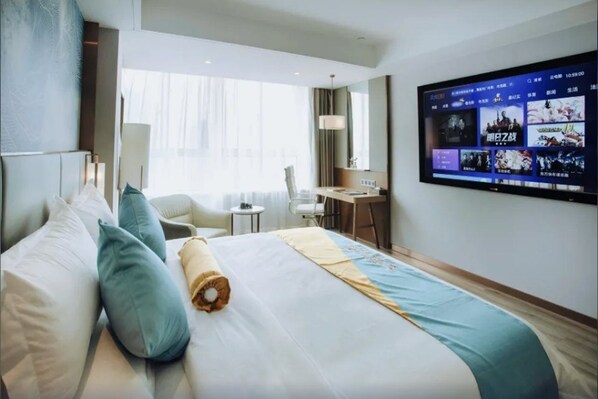 Habitació d'hotel amb un llit gran, escriptori, cadira i televisió que mostra títols de jocs.