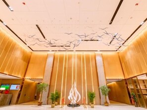 A modern lobby with a central light installation, vertical wooden panels, and potted plants. - Greentree Eastern Suqian Sihong Administrative Center Hotel (Suqian)