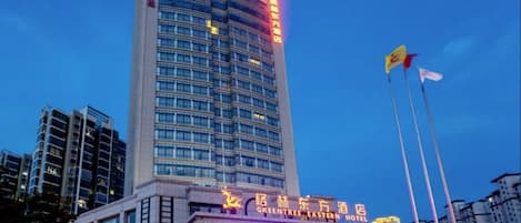 Un edificio alto con un letrero llamativo del Hotel GreenTree Eastern.