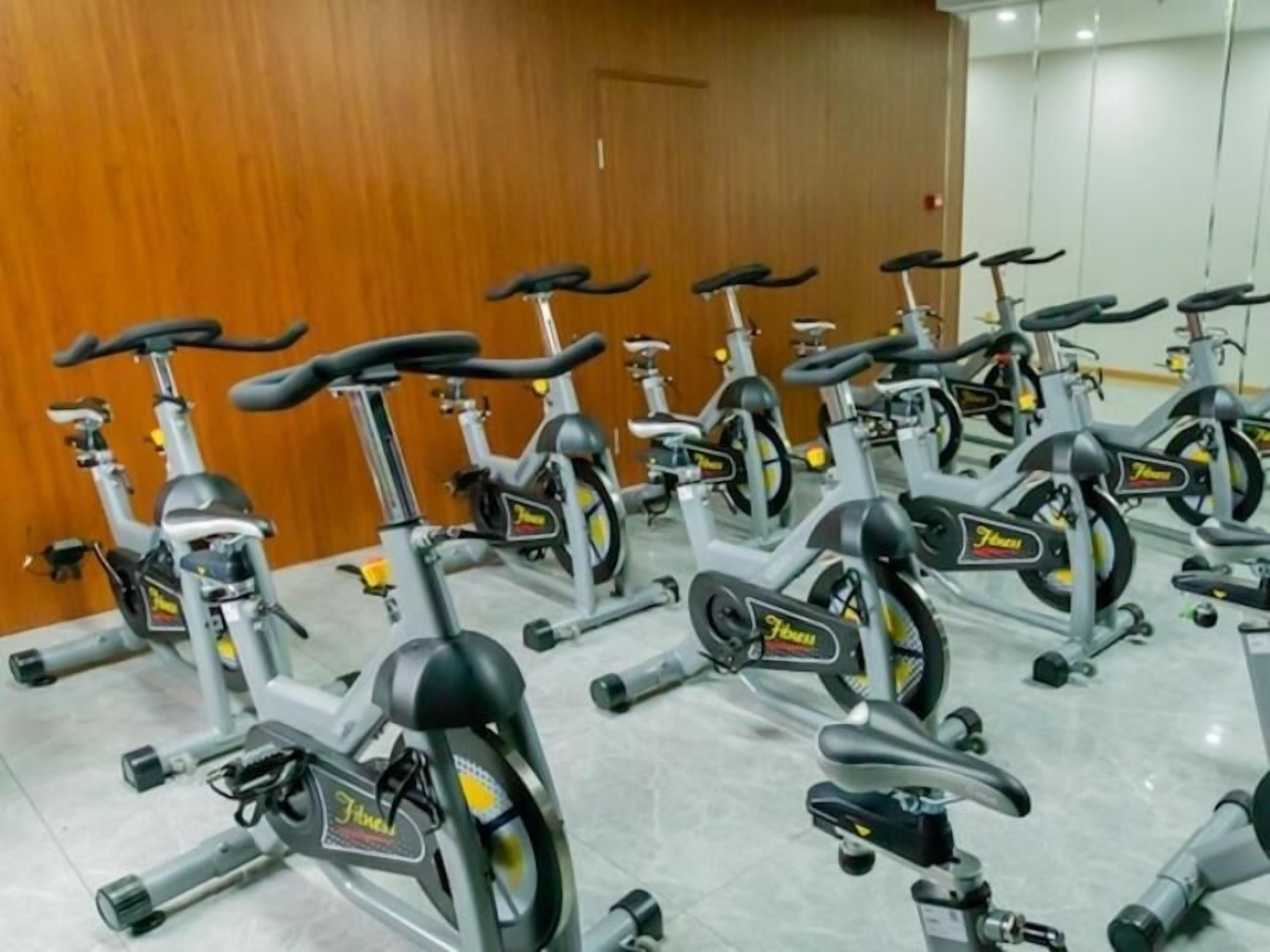 Een rij stilstaande fietsen in een ruimte met een houten wand en betegelde vloer.