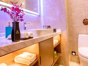 A modern bathroom with a marble countertop, a sink, a toilet, and a shelf with towels. - Greentree Eastern Suqian Sihong Administrative Center Hotel (Suqian)