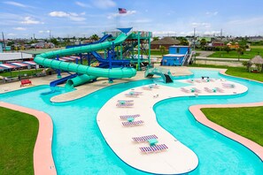 Un parc aquatique doté d’un grand toboggan aquatique, de plusieurs piscines et d’espaces de détente avec des chaises longues.
