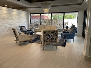 A spacious living room with a modern design, featuring a beige sofa, blue armchairs, and a patterned coffee table. - Beautifully remodeled condo offering breathtaking Gulf views right on the beach. (Marco Island)