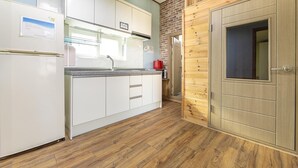 Una cocina con armarios blancos, una puerta de madera y una pared de ladrillo.