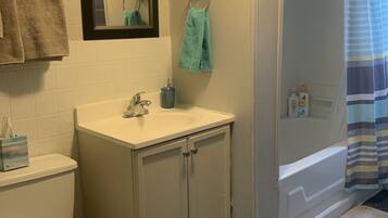 Een bad/douchecombinatie, een haardroger, handdoeken, zeep