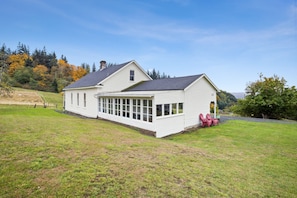 A single-story white house with a large covered porch and a fenced yard.