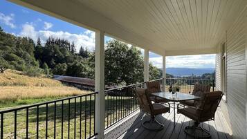 Relax on the covered deck with a table and two chairs, taking in the serene views of the surrounding hills and lush landscape.