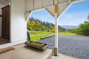 A covered porch with a view of a green landscape and mountains. - 1910 Vintage Ranch House with beautiful views (Kalama)