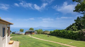A grassy area with a path, a small building, and a view of the sea and mountains. - Analipsi Villas Beach Front 5, Kastro Kyllini, Greece (Kastro Kyllini)