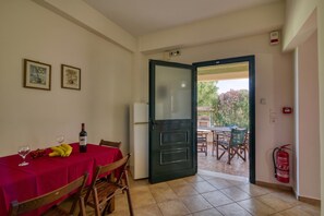 A dining area with a table set for two, a refrigerator, and a door leading to an outdoor patio. - Analipsi Villas Beach Front 5, Kastro Kyllini, Greece (Kastro Kyllini)