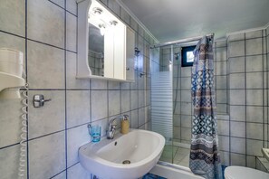A bathroom with a sink, mirror, and shower curtain.