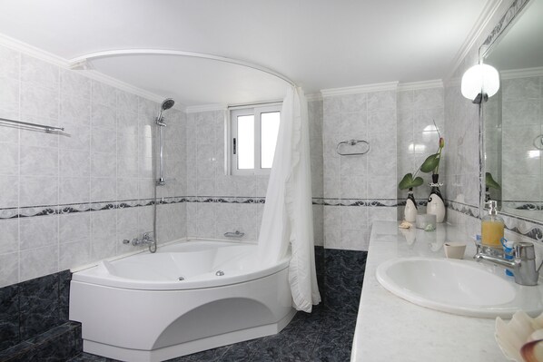 A modern bathroom with a freestanding bathtub, a vanity with a sink, and a large mirror.