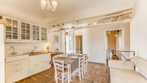 A spacious kitchen with white cabinetry, a dining table set for four, and a cozy seating area with a sofa. - Terrazza Apuana A Few Steps From The Sea, Forte dei Marmi, Italy (Forte dei Marmi)