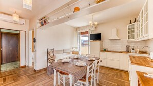 A kitchen with white cabinets, a dining table set for four, and a wooden herringbone floor. - Terrazza Apuana A Few Steps From The Sea, Forte dei Marmi, Italy (Forte dei Marmi)