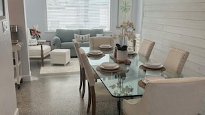 Uma área de refeições com mesa de vidro, cadeiras e ventilador de teto.
