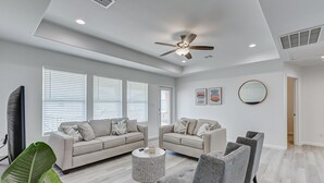 A spacious living room with two sofas, a coffee table, and a ceiling fan. - Livin' Lobster - New, Near Beach🌊🏖 , Sleeps 8, Pet Friendly🐶, 📍Central Location (Bolivar Peninsula)