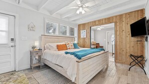 Een slaapkamer met een houten bed, een plafondventilator, een televisie en een houten wandpaneel.