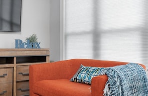 Quarto com um armário de madeira, um sofá vermelho e um cobertor azul estampado.