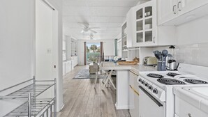 Een moderne keuken met witte kastjes, een centraal eiland en een fornuis.