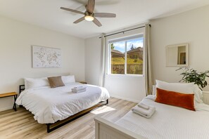 Relax in this serene bedroom with a large bed, ceiling fan, and a window offering a view of the outdoors.