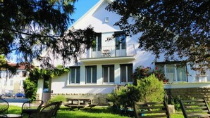 A two-story building with a balcony, surrounded by a well-maintained garden with a picnic table and benches. - App*** 2/3 pers "Nuage" ☁️ Air-conditioned with garden (Lons-le-Saunier)