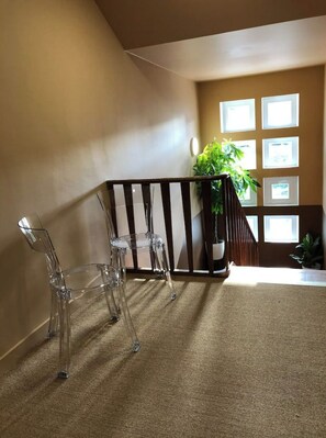 A room with a wooden railing, a clear glass table, and a potted plant near a window.