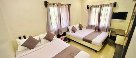 A hotel room with two beds, a flat-screen TV, and a ceiling fan.