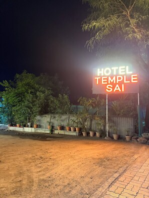A sign for 'HOTEL TEMPLE SAI' with a paved path and potted plants in the foreground. - Hotel Temple Sai (Rahata)