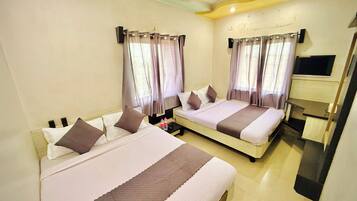 A hotel room with two beds, a flat-screen TV, and a ceiling fan.