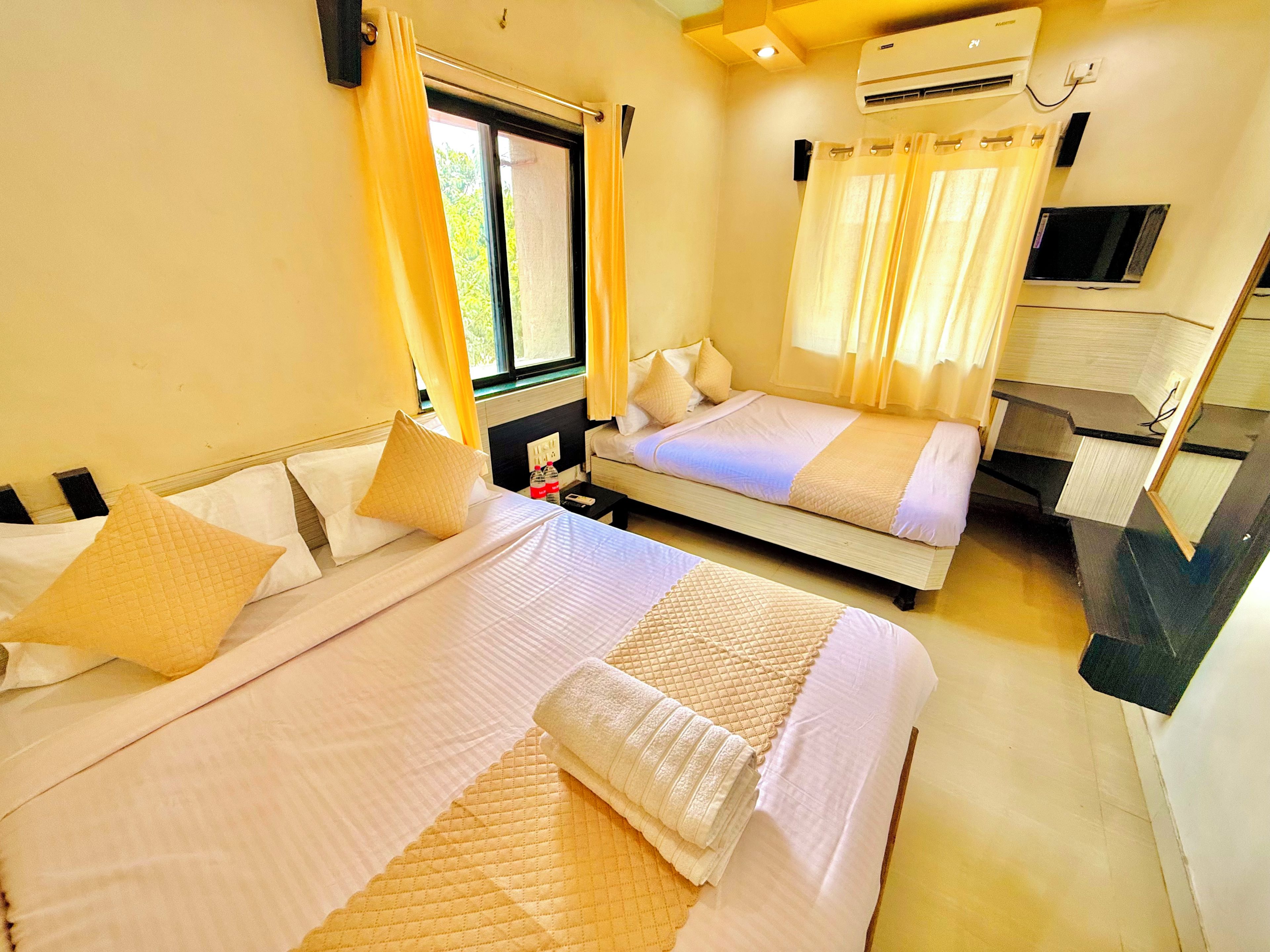 A hotel room with two beds, a TV, and a window with curtains.