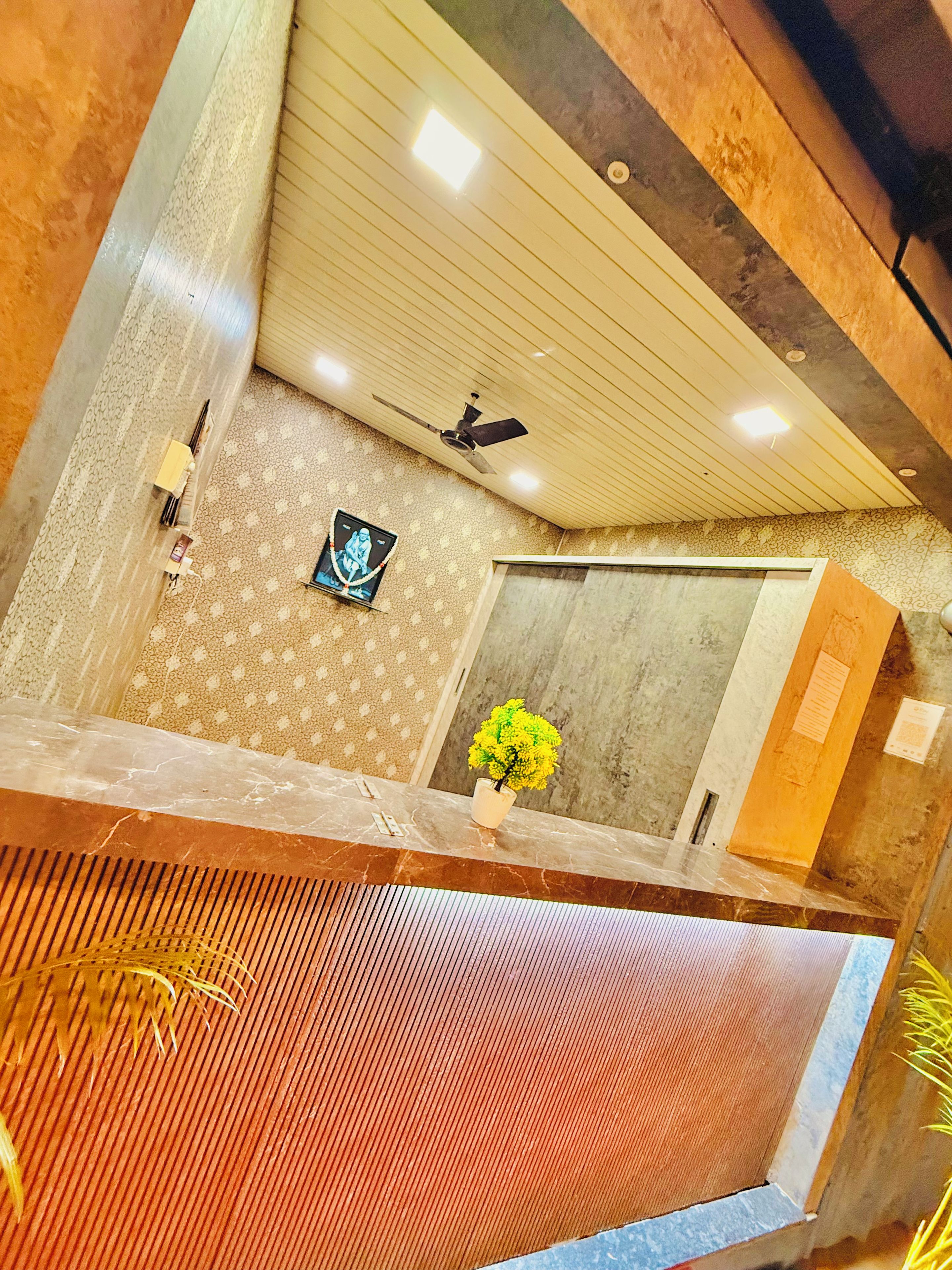 A room with a ceiling fan, a framed picture, a potted plant, and a marble reception desk.