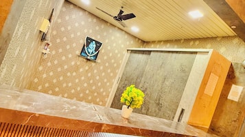 A room with a ceiling fan, a framed picture, a potted plant, and a marble reception desk.
