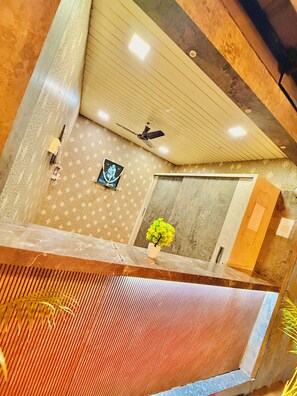 A room with a ceiling fan, a framed picture, a potted plant, and a marble reception desk. - Hotel Temple Sai (Rahata)