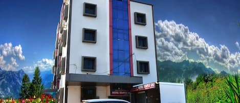 A hotel with a white facade, a blue vertical stripe, and a sign reading "HOTEL TEMPLE SAI".