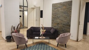 Un salon avec un canapé noir, deux fauteuils, une table basse et un vase décoratif.