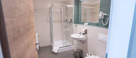 Une salle de bain moderne avec une douche à parois de verre, un lavabo blanc et des toilettes.