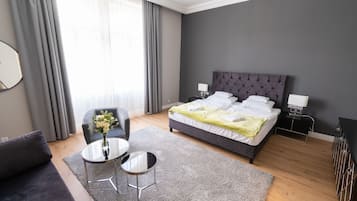 Una habitación de hotel moderna con una cama grande, una pequeña mesa redonda, un sofá y una silla.