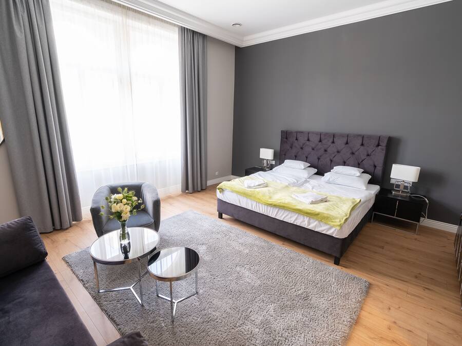 Una habitación de hotel moderna con una cama grande, una pequeña mesa redonda, un sofá y una silla.