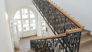 A staircase with ornate black railings and wooden steps, leading to an upper floor.