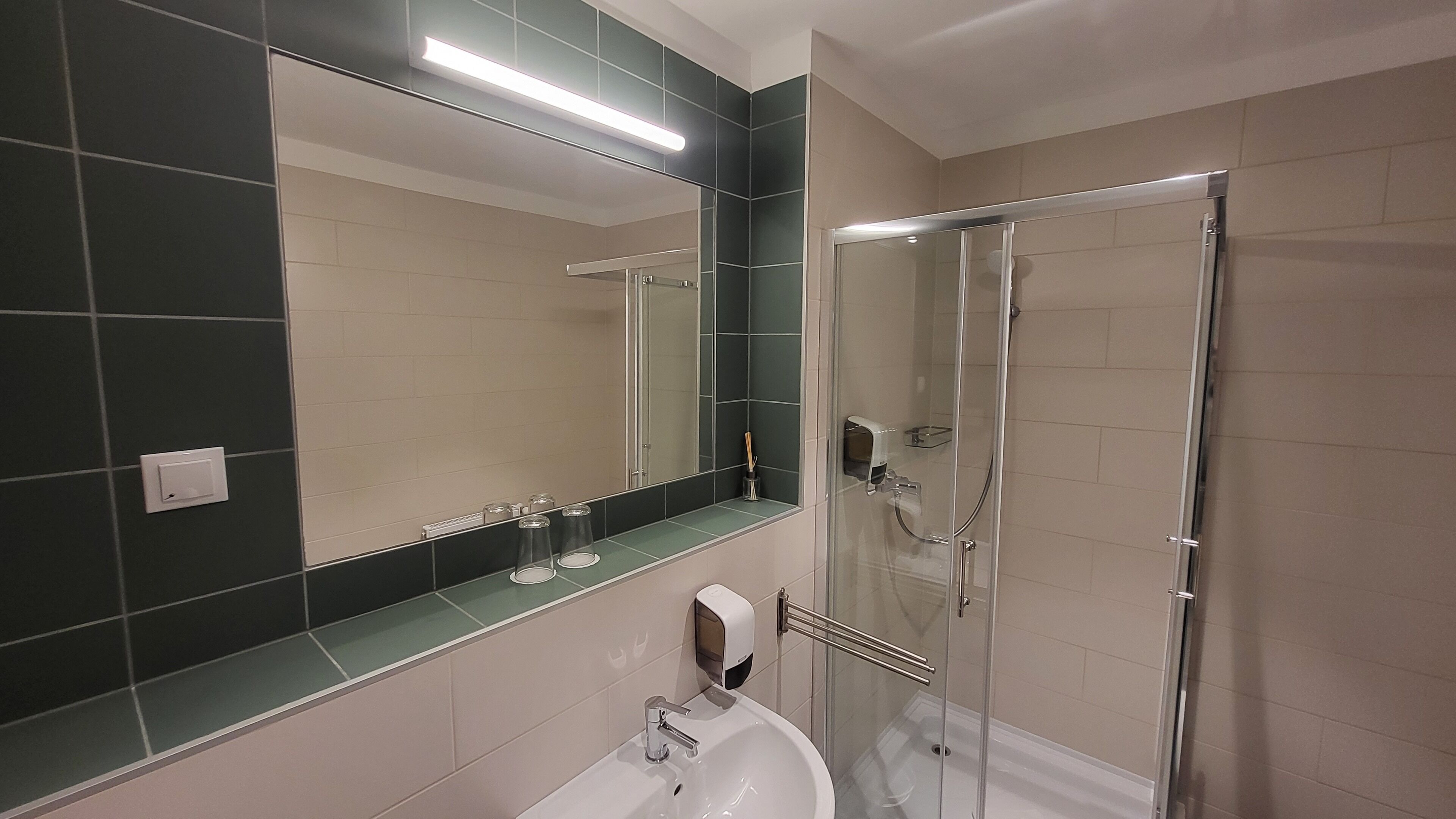 A modern bathroom with a large mirror, a glass shower enclosure, and a white sink.