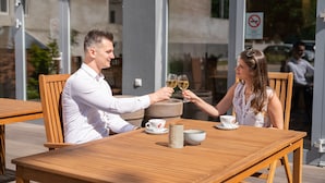 Une table en bois sur laquelle se trouvent une tasse et une soucoupe blanches, un bol blanc et un verre de vin blanc.