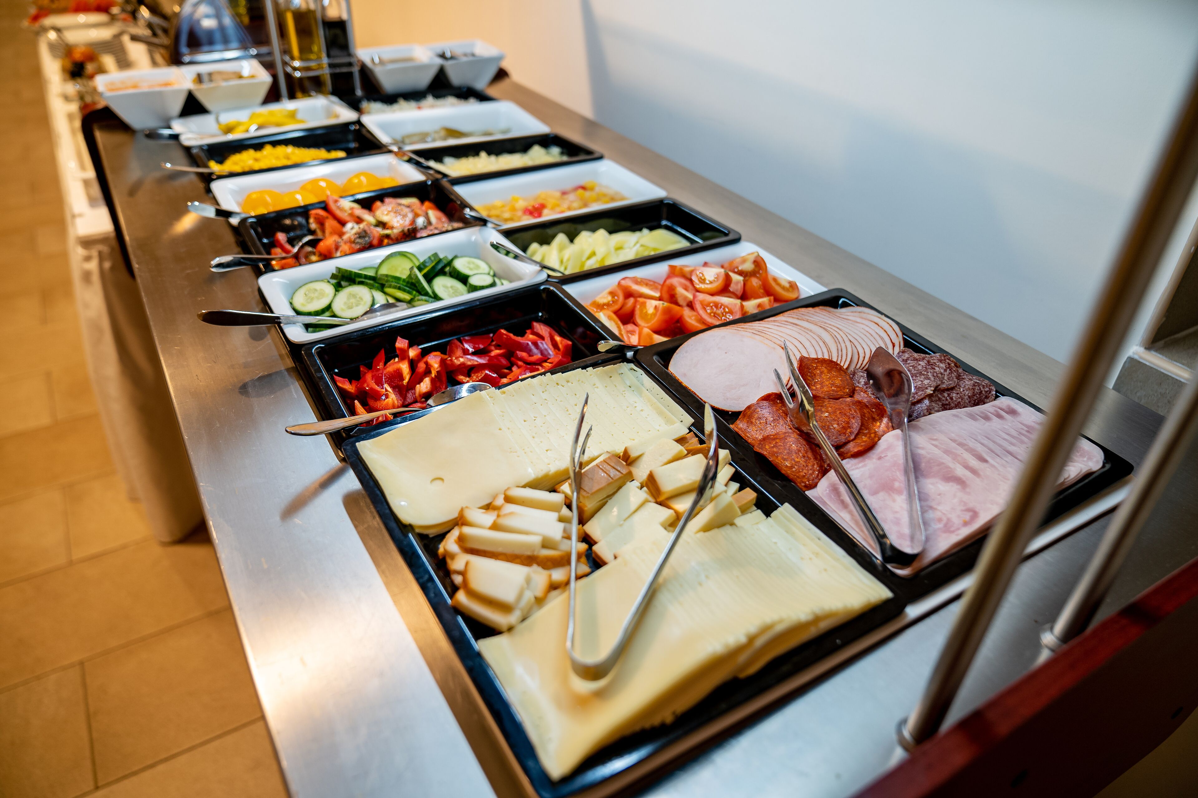 Ein Buffet mit verschiedenen Speisen, darunter Fleisch, Käse und Gemüse.