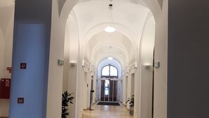 Un couloir d’hôtel avec des plafonds en forme d’arc, une porte tournante et des plantes en pot.