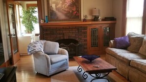Ein Wohnzimmer mit Kamin, einer Couch, einem Sessel und einem Couchtisch.