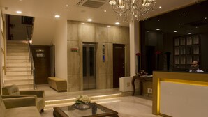 Un hall con mostrador de recepción, una escalera y una zona de estar con una mesa baja de vidrio.