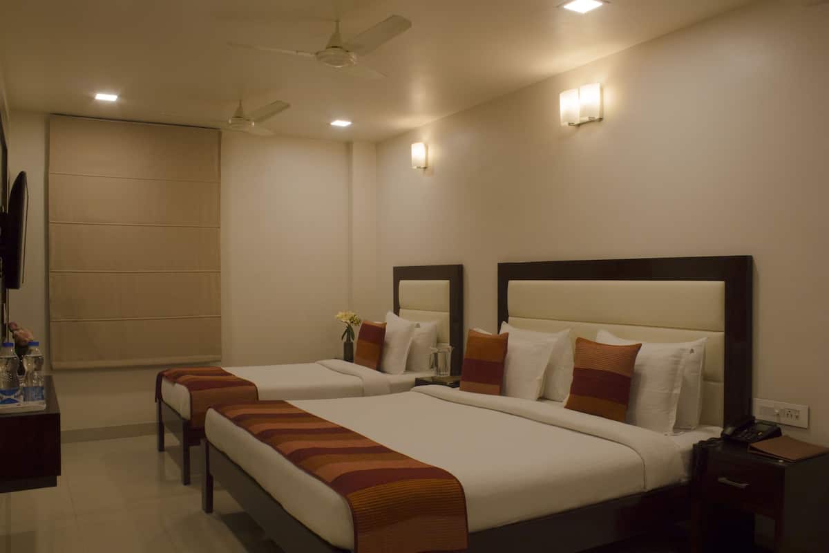 A hotel room with two beds, a ceiling fan, bedside lamps, a nightstand, and a TV.