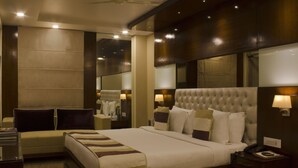 Una habitación de hotel con una cama grande, lámparas de noche, una mesita de noche y un espejo.