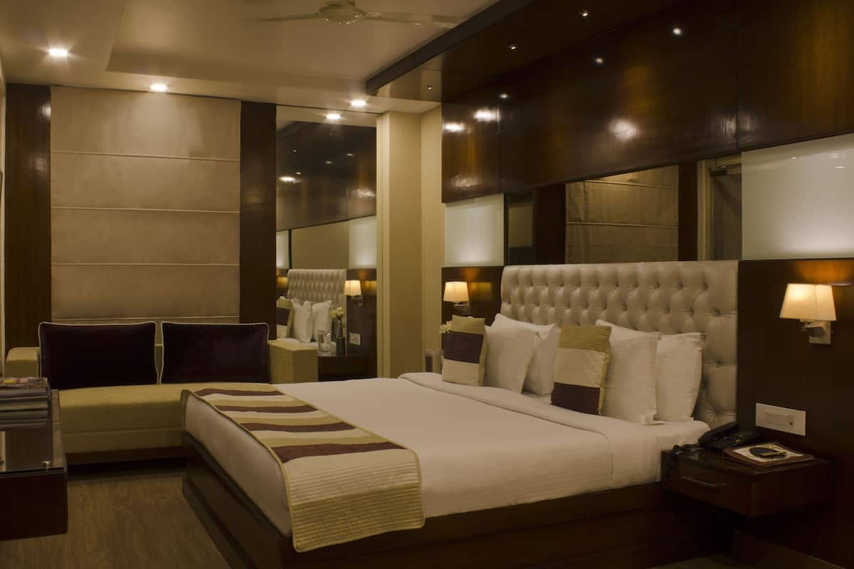 A hotel room with a large bed, bedside lamps, a nightstand, and a mirror.